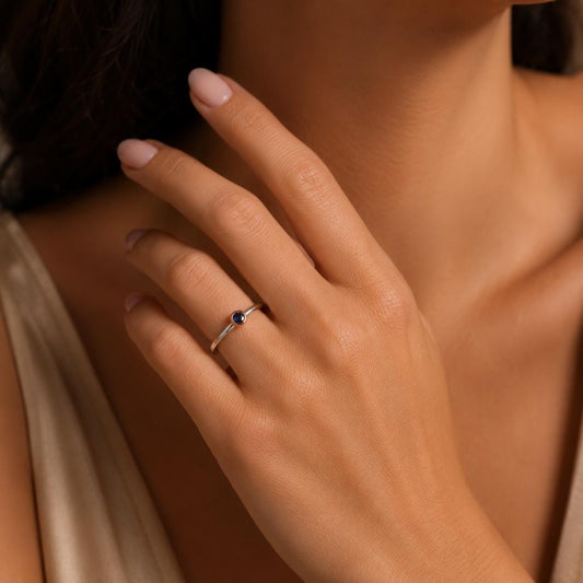 A close-up of a person's hand wearing a ring with a gemstone.
