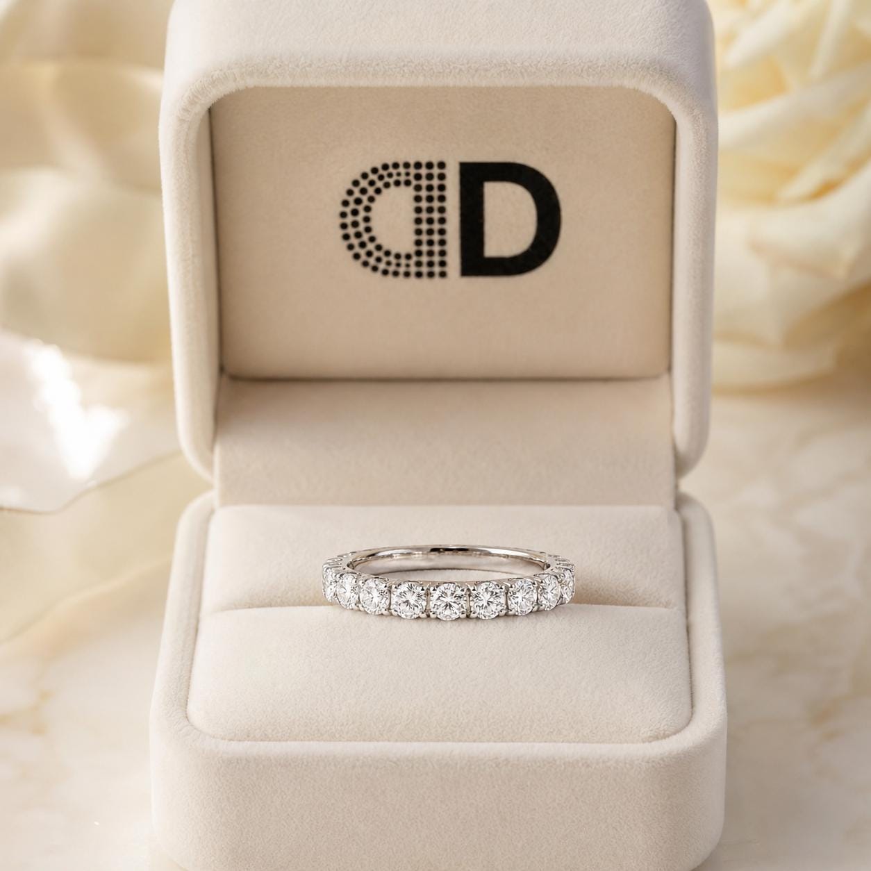 A diamond ring is displayed in a white jewelry box with a logo on the lid.