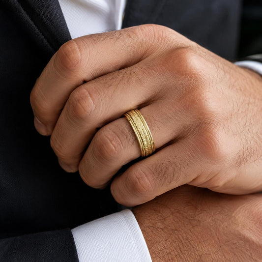 A close-up image of a man's hand wearing a gold ring on the ring finger.