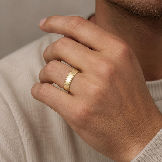 A close-up of a person's hand wearing a gold ring on the ring finger.