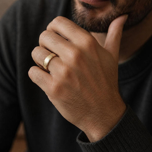A close-up of a hand wearing a gold ring, with a thoughtful expression on the person's face.