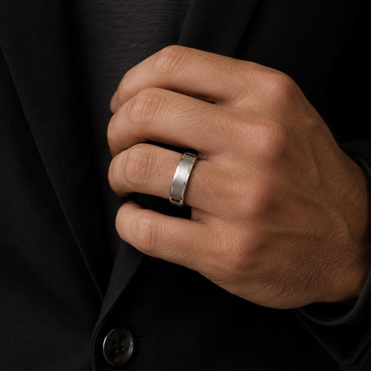 A close-up of a person's hand wearing a silver ring on the ring finger.