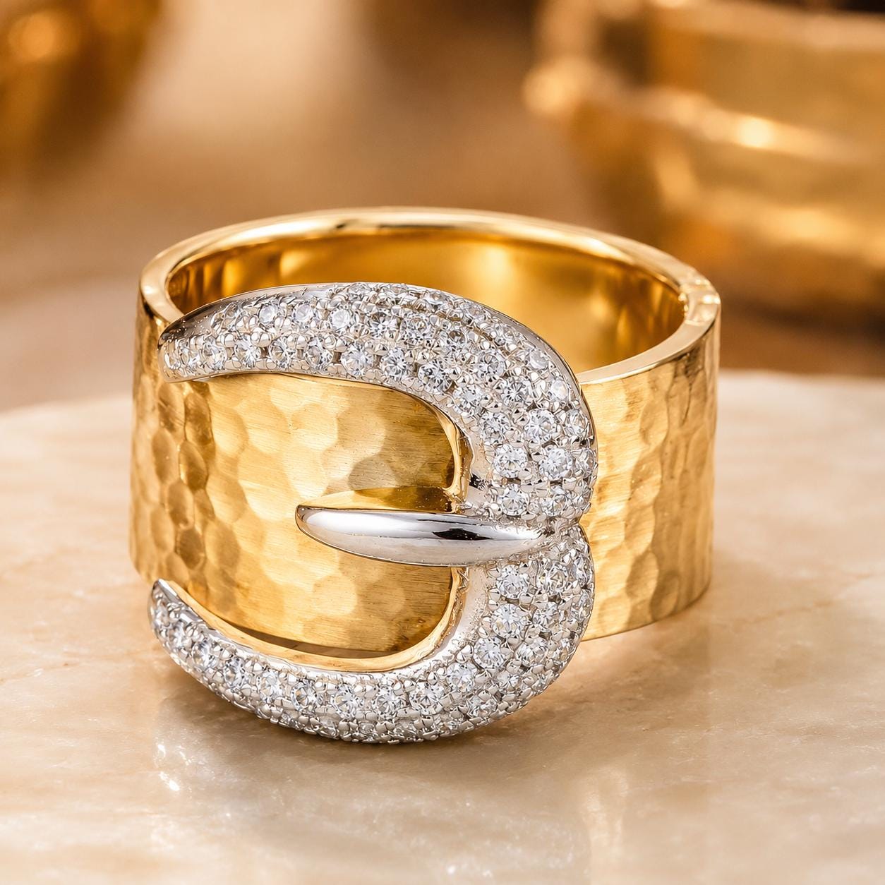A gold ring with a large diamond-encrusted buckle, showcasing a luxurious and elegant design.