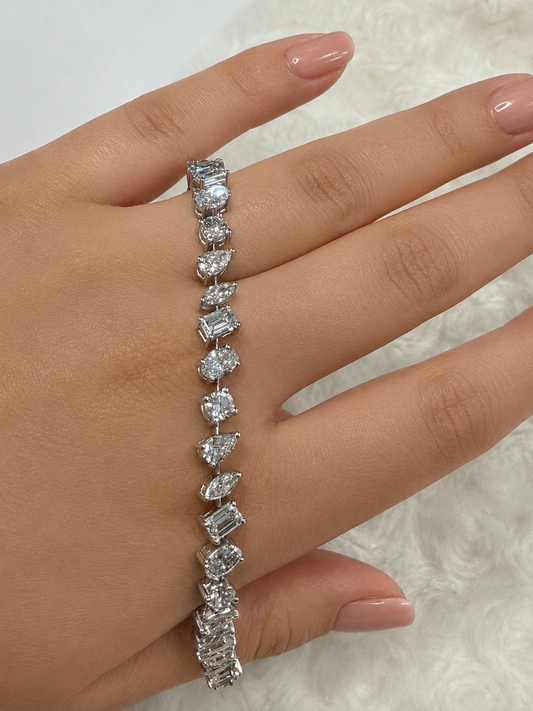 A close-up image of a person's hand wearing a bracelet with a row of diamond-encrusted stones.