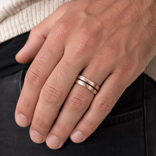 A close-up of a person's hand wearing a gold ring on the ring finger.