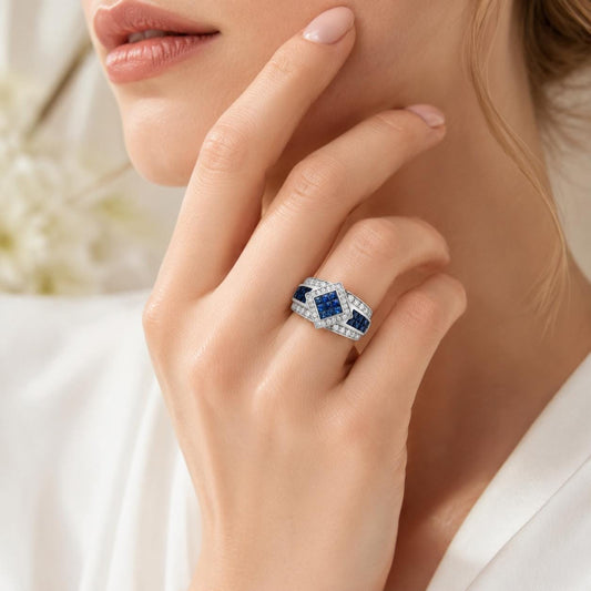 A close-up of a woman's hand wearing a diamond ring with blue gemstones.
