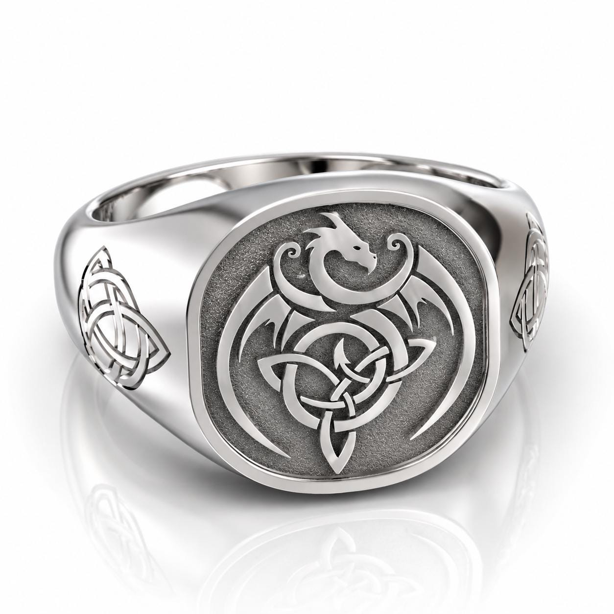 A silver ring with a dragon design and Celtic knot patterns.