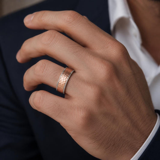 A close-up of a person's hand wearing a ring, with a suit jacket visible in the background.