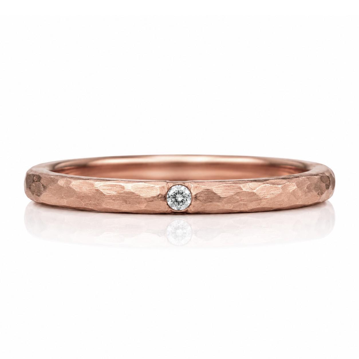 A rose gold ring with a single diamond set in the center.