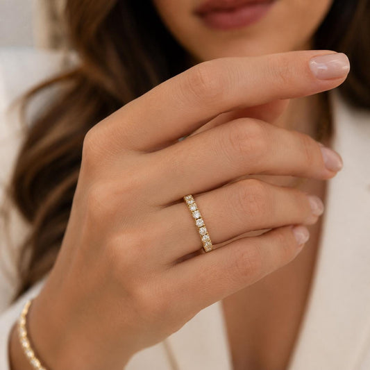 A close-up of a person's hand wearing a gold ring with a row of small diamonds.