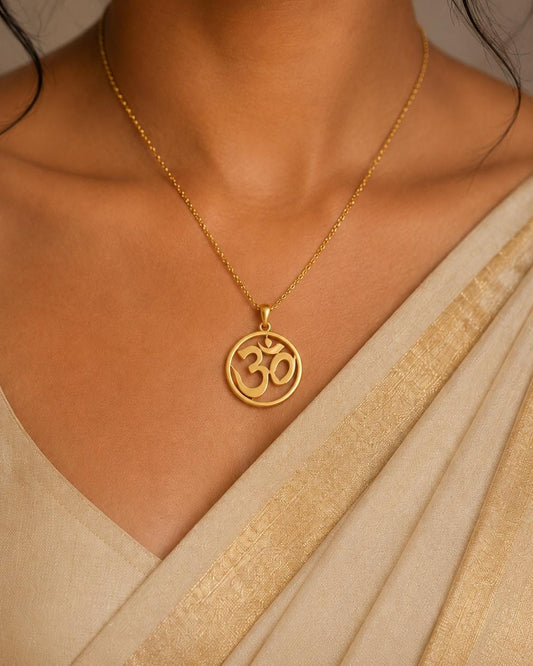 A gold necklace with a pendant featuring the Om symbol, a significant symbol in Hinduism and yoga.