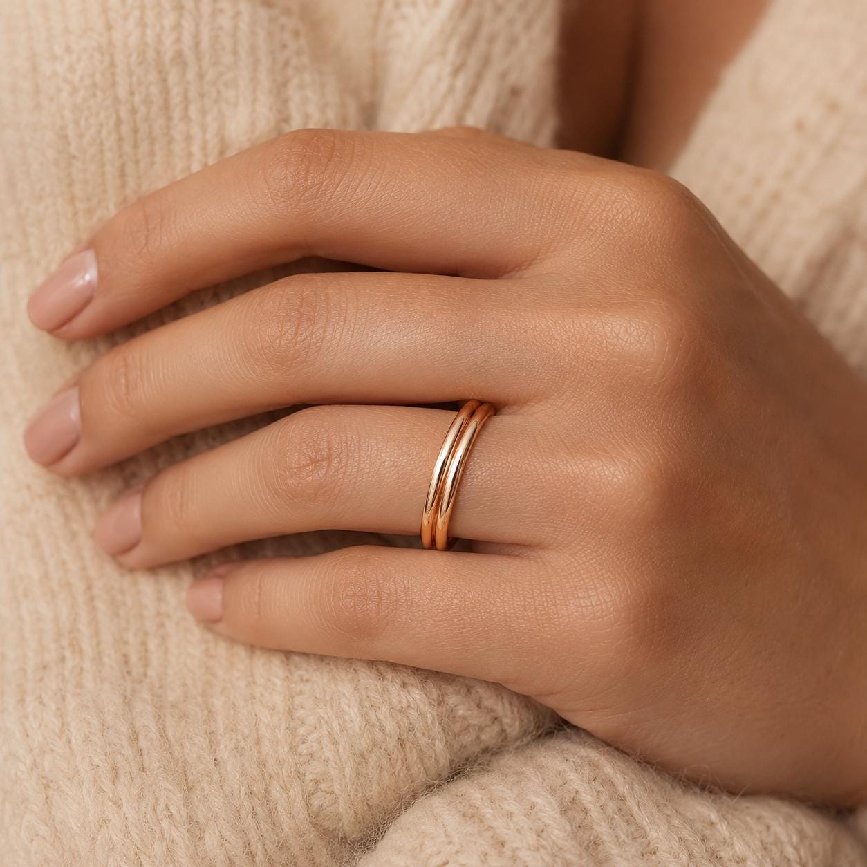 A close-up of a person's hand wearing a gold ring on the ring finger.