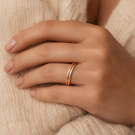 A close-up of a person's hand wearing a gold ring on the ring finger.