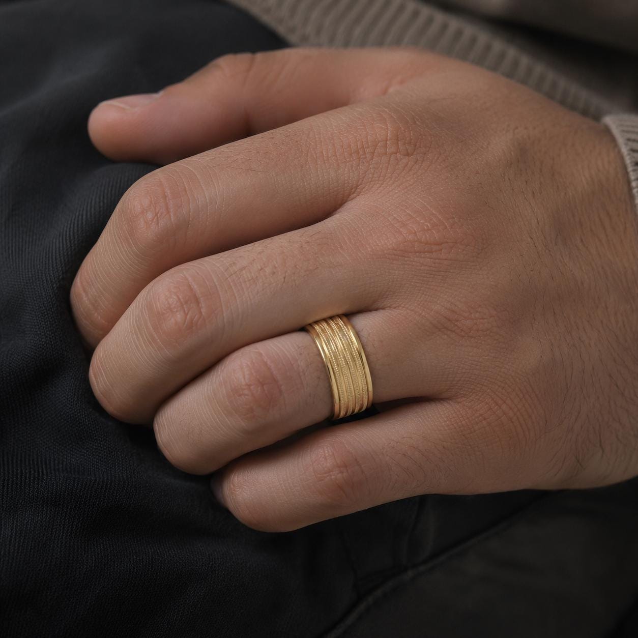 A close-up image of a person's hand wearing a gold ring on the ring finger.