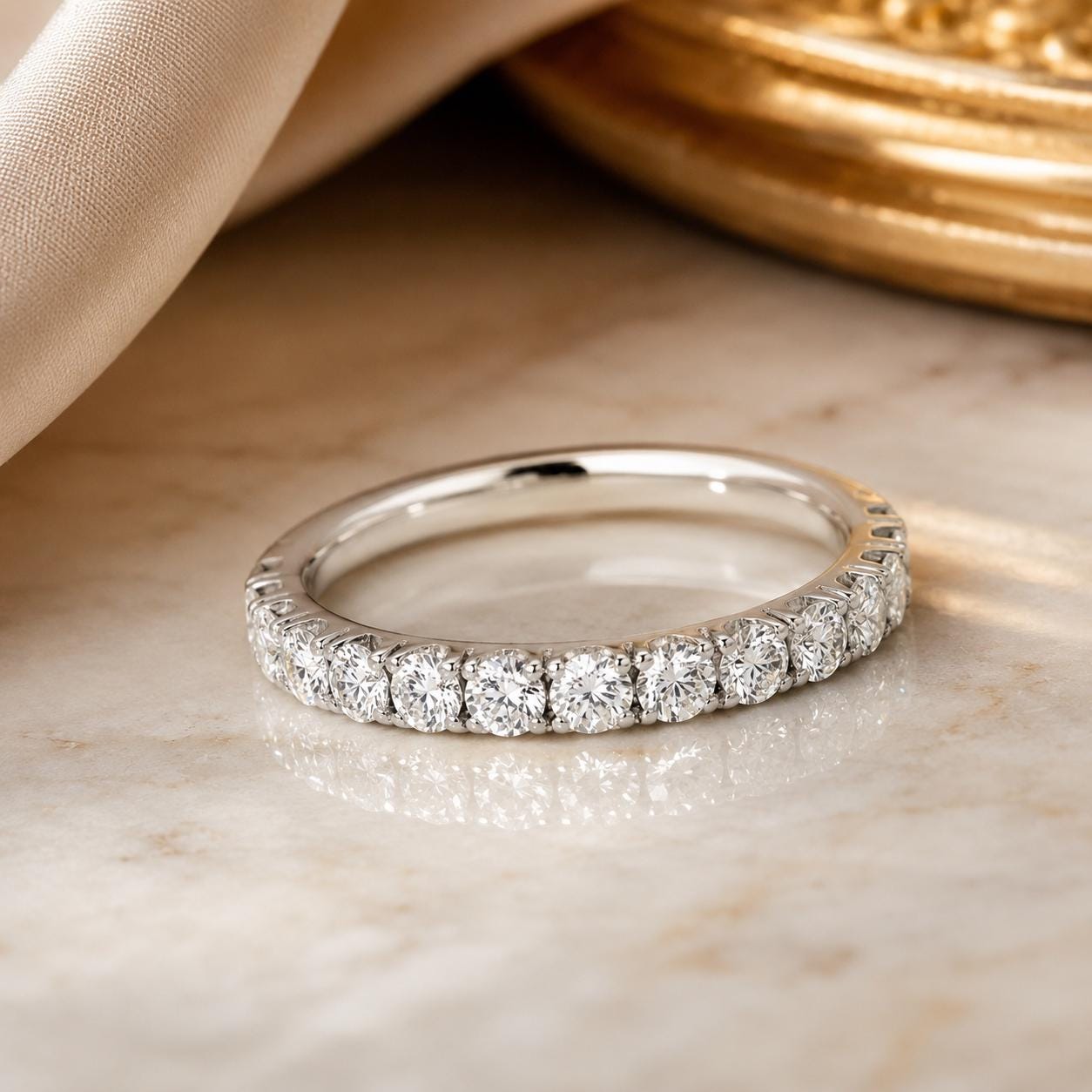 A diamond-encrusted ring with a row of diamonds set in a silver band is displayed on a marble surface.