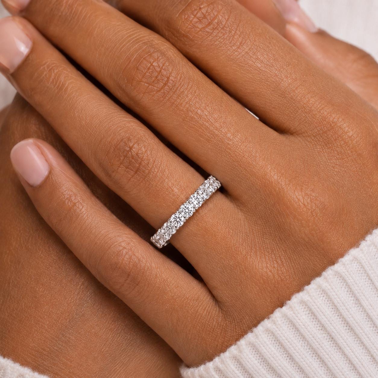 A close-up of a person's hand wearing a diamond ring on the ring finger.