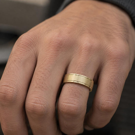 A close-up of a person's hand wearing a gold wedding ring.