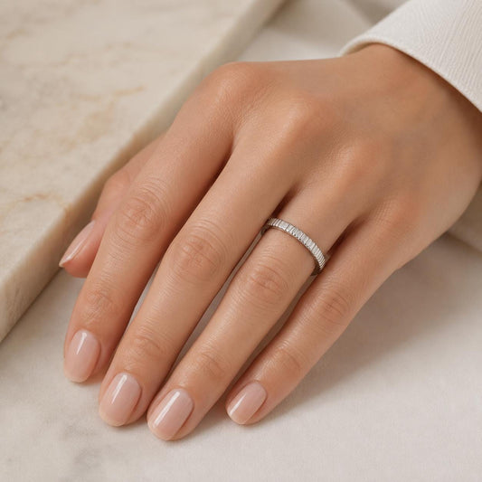 A close-up of a hand wearing a ring on the ring finger.