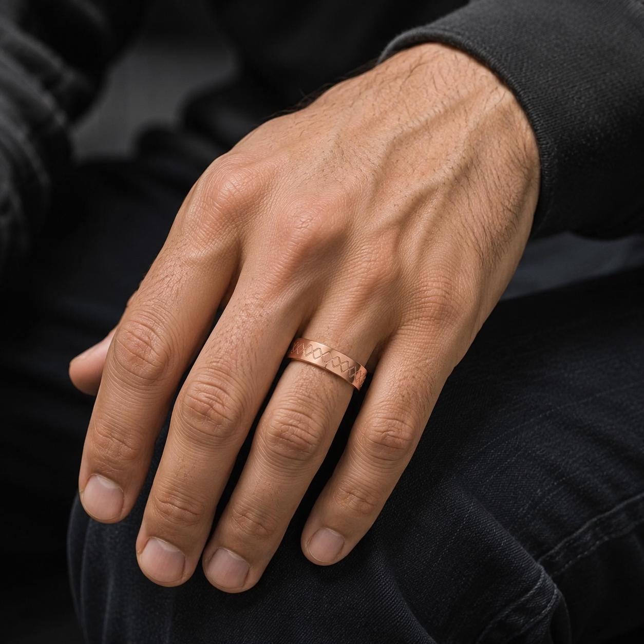 A close-up of a person's hand wearing a copper-colored ring on the ring finger.