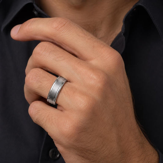 A close-up of a person's hand wearing a silver ring on the ring finger.