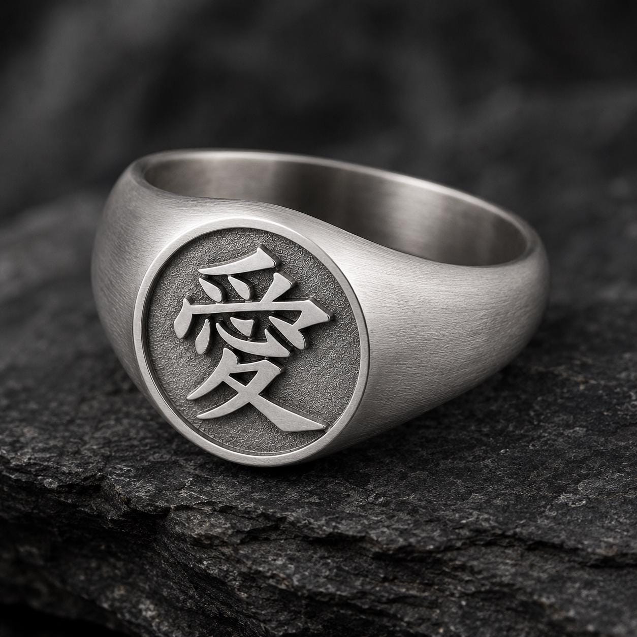 A silver ring with a circular design featuring an Asian character, likely a symbol or deity, in the center.
