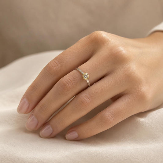 A close-up of a hand wearing a ring with a small diamond.