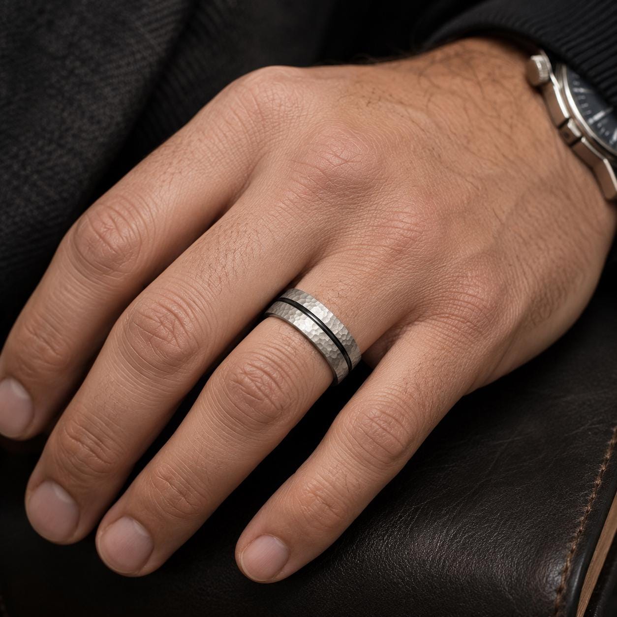 A close-up of a person's hand wearing a silver ring on the ring finger.