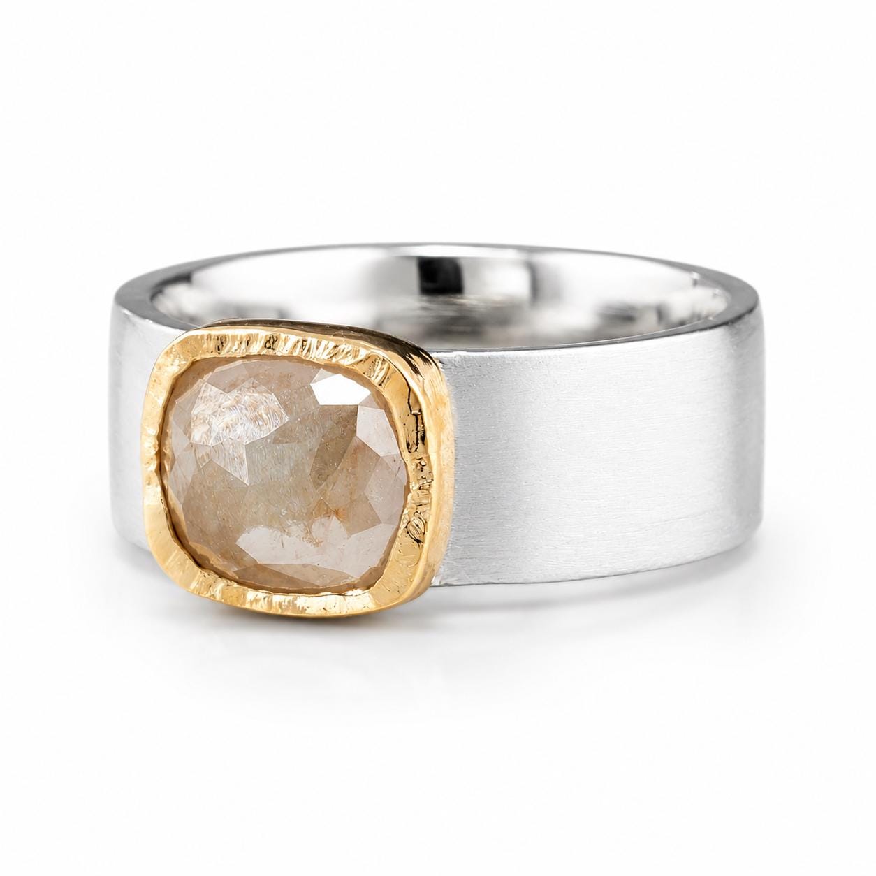A silver ring with a large, irregularly shaped diamond set in a gold-colored frame.