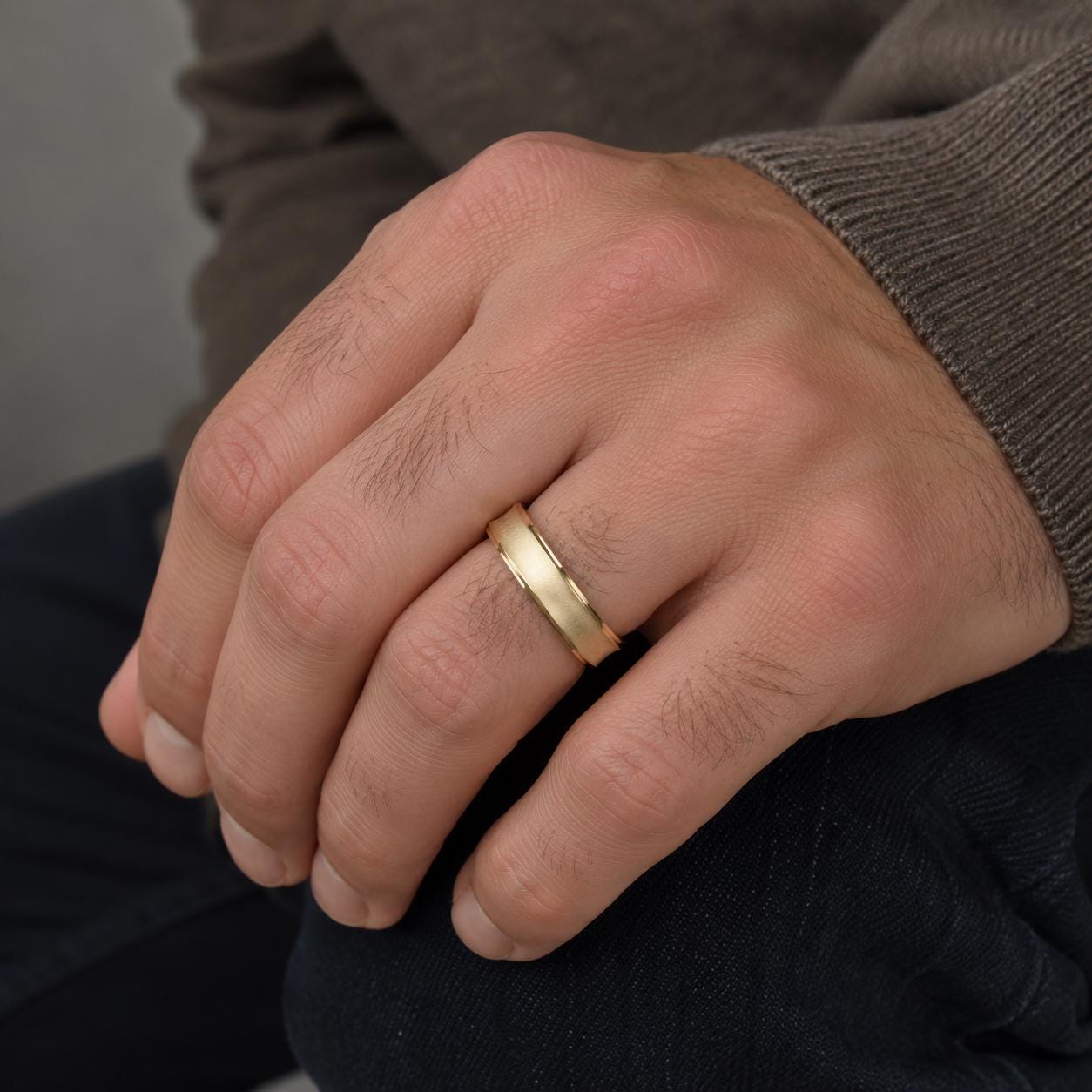 A close-up of a person's hand wearing a gold wedding ring.