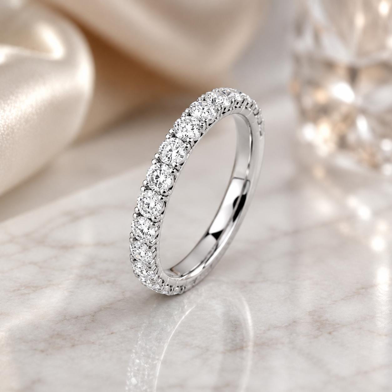 A diamond-encrusted ring with a row of diamonds set in a band, resting on a marble surface.