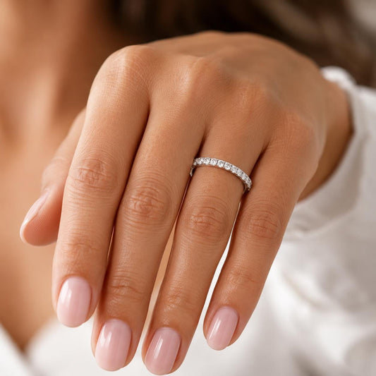A close-up of a person's hand wearing a diamond band ring.