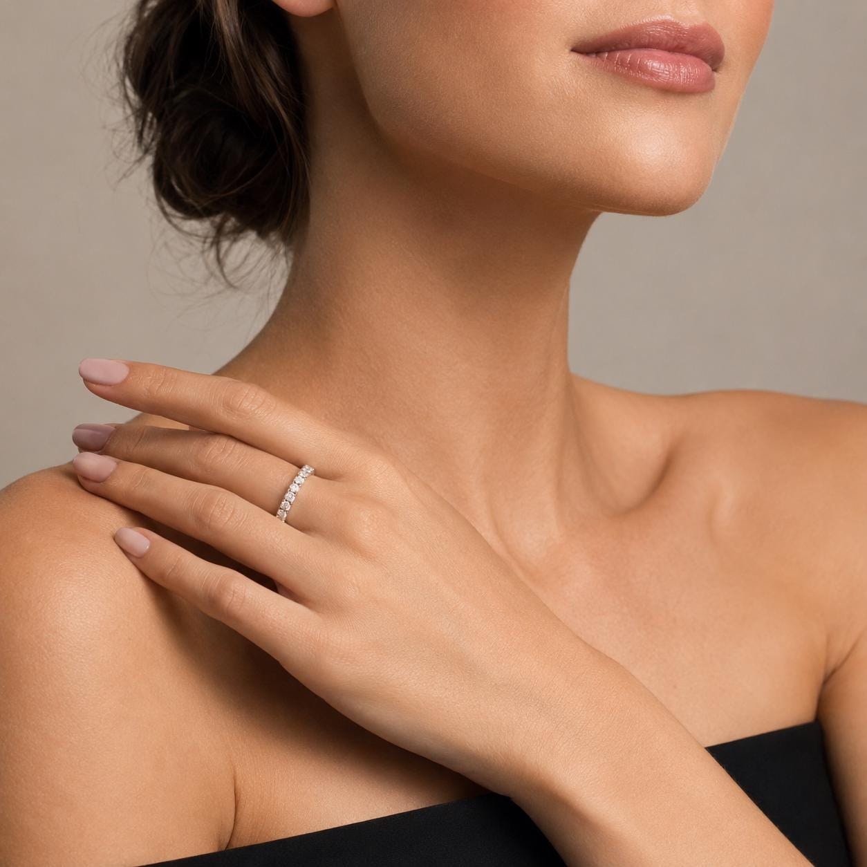 A close-up of a woman's hand wearing a diamond ring, with her chin and neck visible.