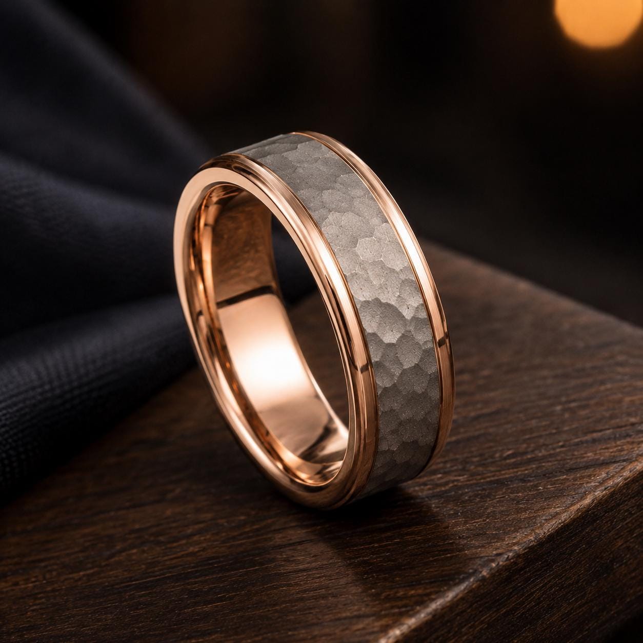 A gold-toned ring with a textured metal band is displayed on a wooden surface, with a blurred background.