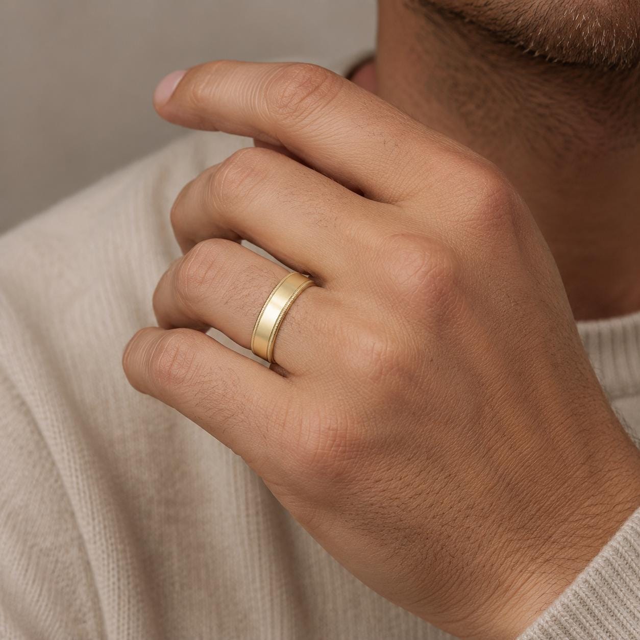 A close-up of a person's hand wearing a gold ring on the ring finger.