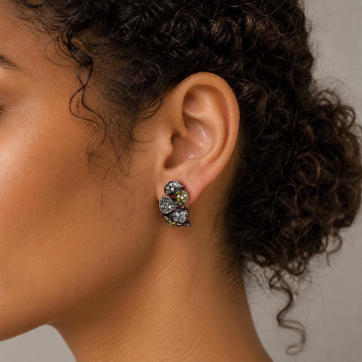 A close-up of a woman's ear with a pair of earrings featuring a floral design.