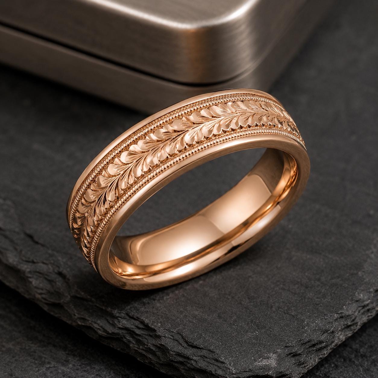 A gold-colored ring with an intricate leaf-like design on the band is displayed on a dark surface.