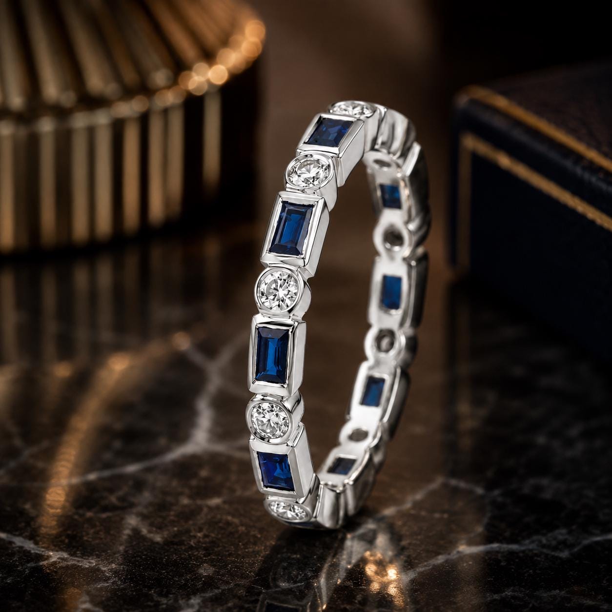 A silver ring with blue gemstones, including blue sapphires, is displayed on a marble surface.