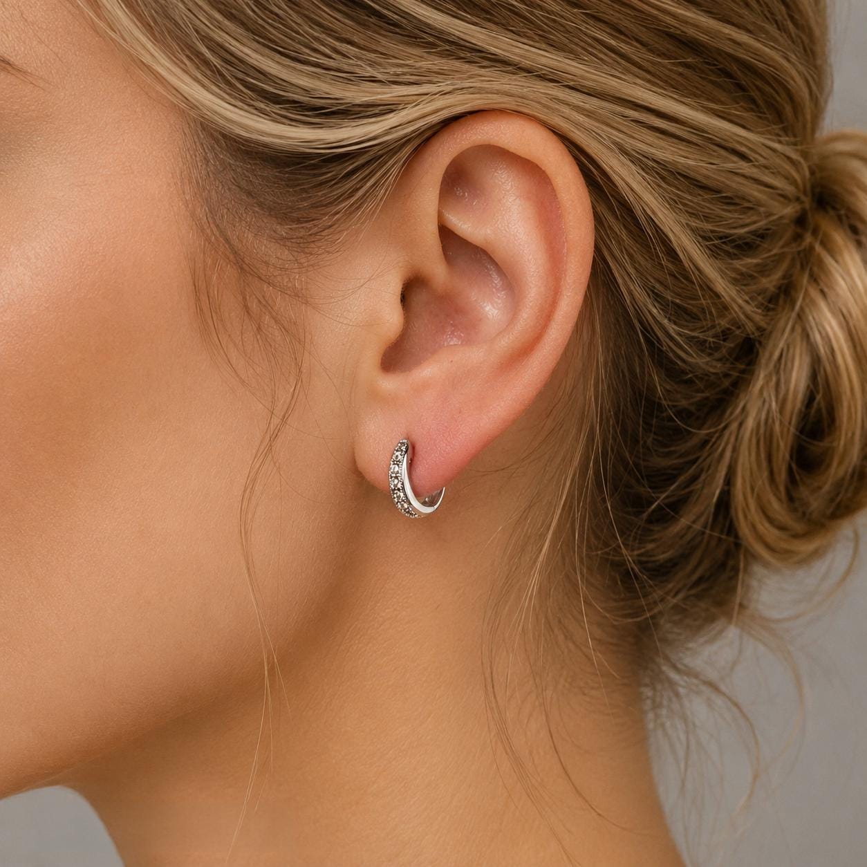 A close-up of a woman's ear with a silver hoop earring.