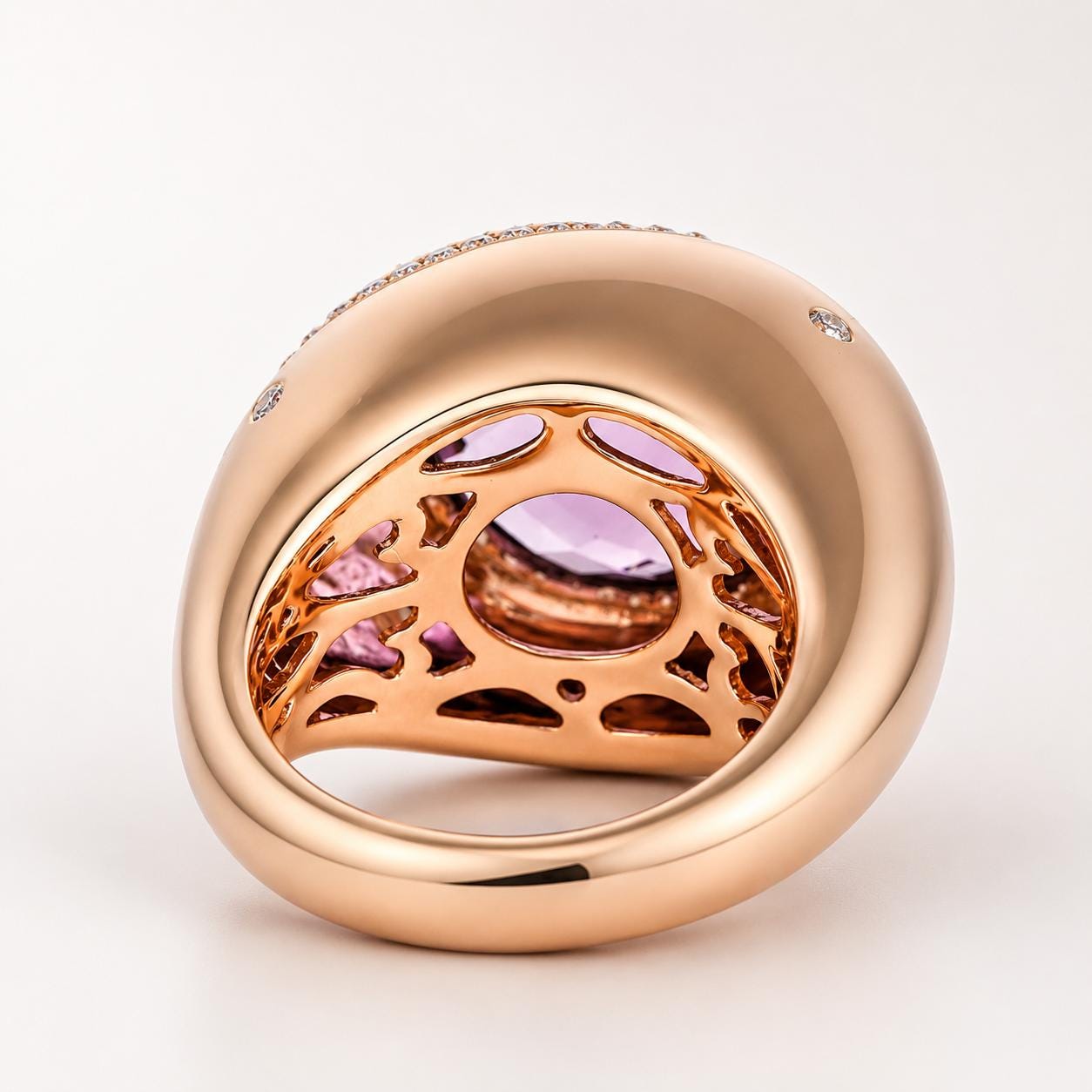 A gold ring with a large purple gemstone set in the center, surrounded by a pattern of smaller diamonds.