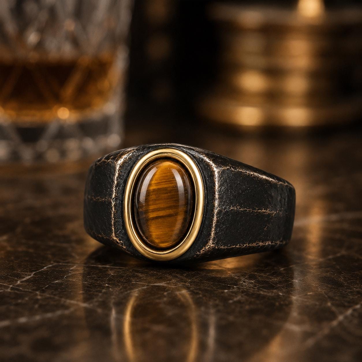 A close-up image of a black leather ring with a gold-colored gemstone, placed on a marble surface.