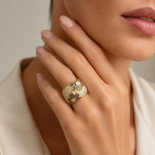 A close-up of a woman's hand wearing a gold ring with a large, ornate design.