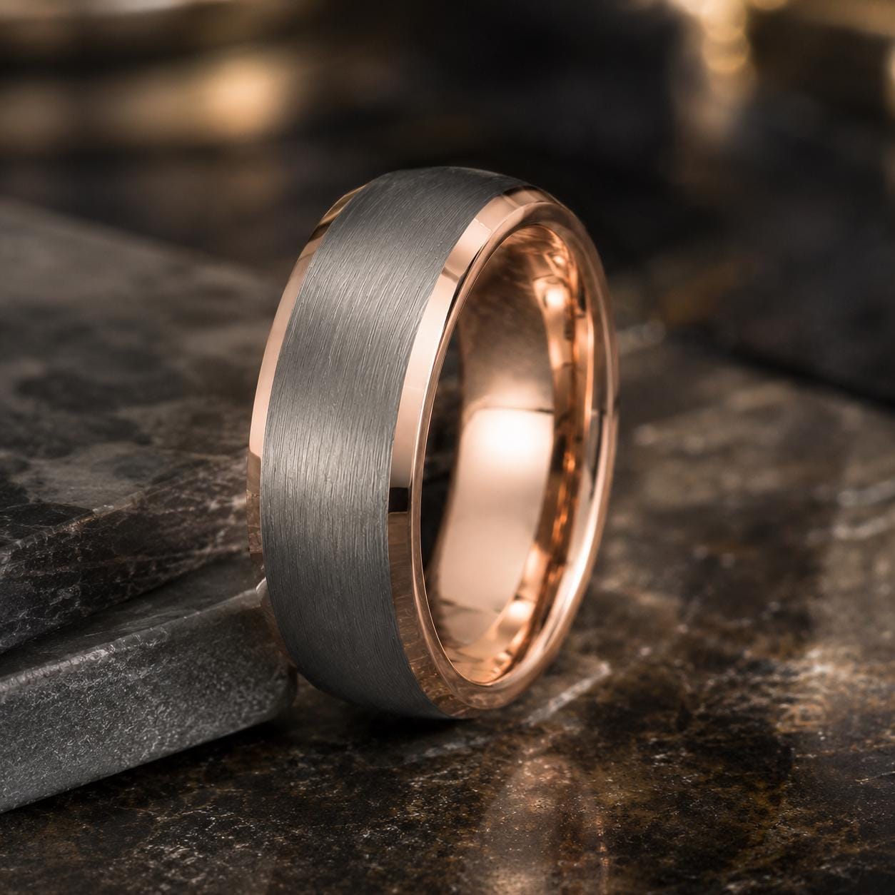 A silver-toned ring with a copper-colored band is displayed on a dark surface, creating a striking contrast.