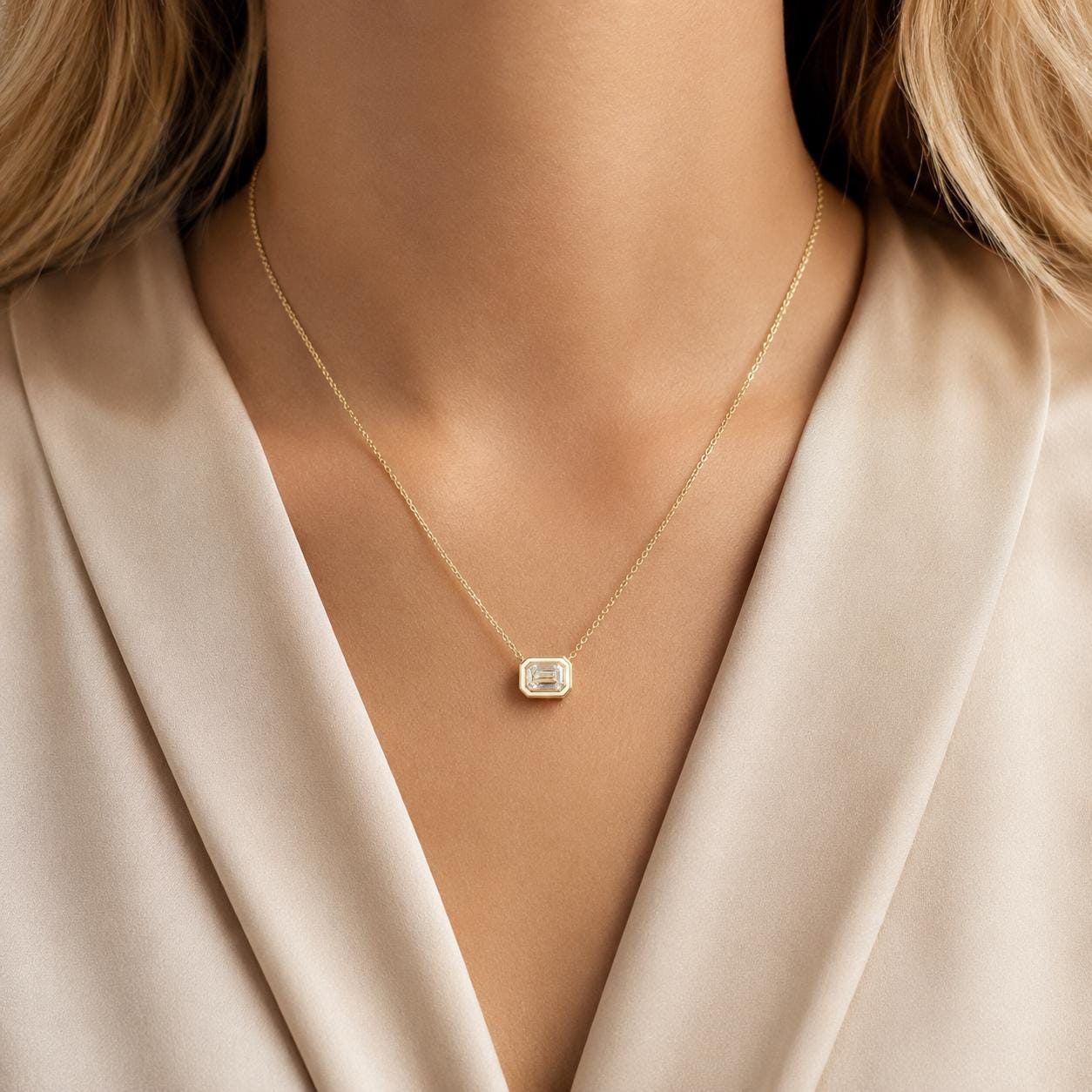 A close-up of a woman's neck wearing a gold necklace with a small diamond pendant.