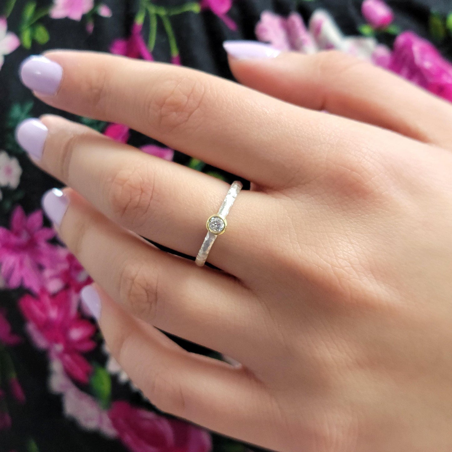 A close-up of a person's hand wearing a ring with a small diamond.