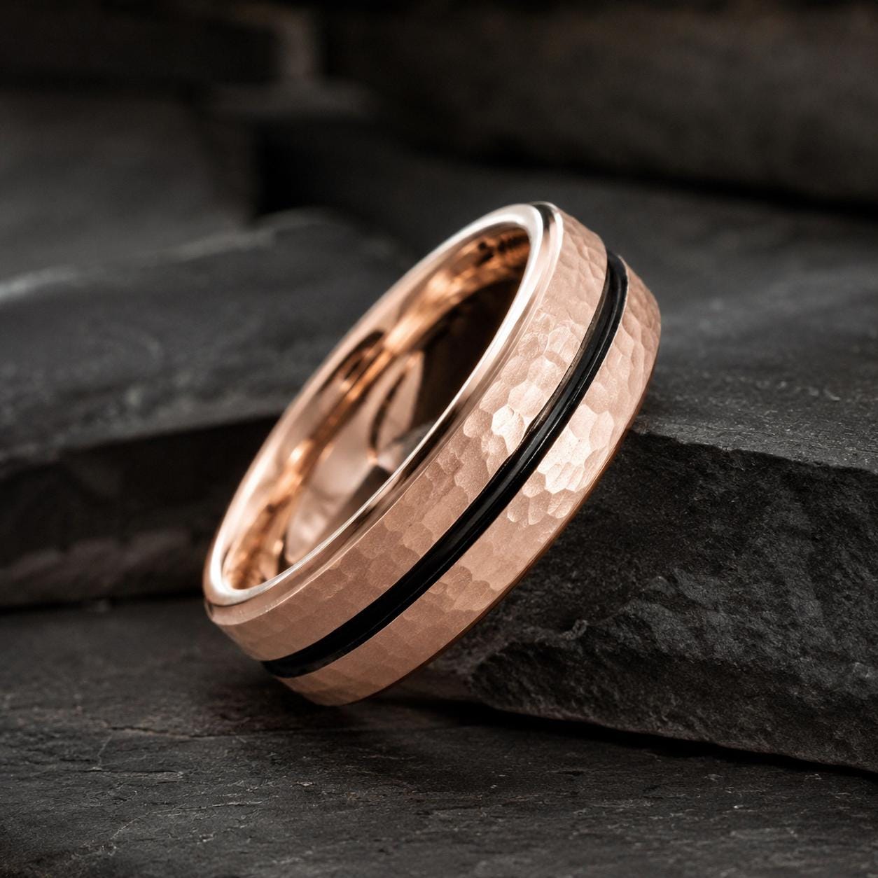 A close-up image of a gold-colored ring with a black band, resting on a dark surface.