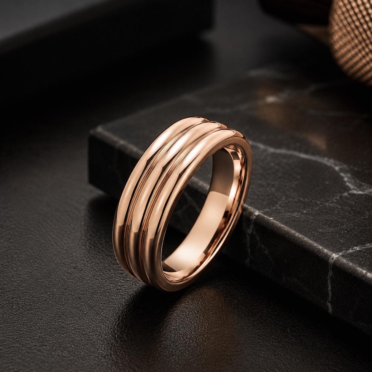 A gold-colored ring with a three-band design is resting on a black surface.