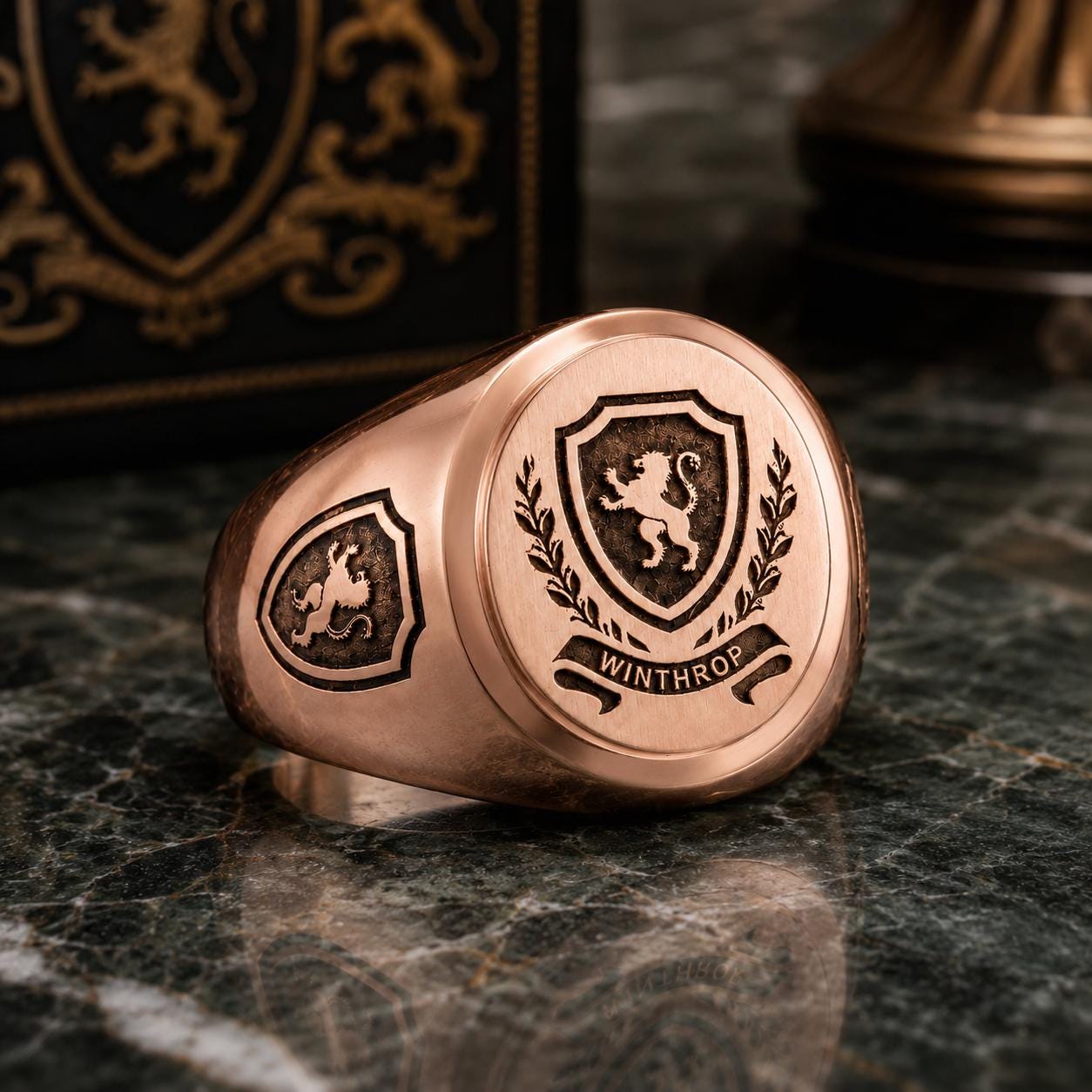 A copper-colored ring with a shield-shaped emblem featuring a lion and laurel wreath, along with the word "WINTHROP" engraved on it.