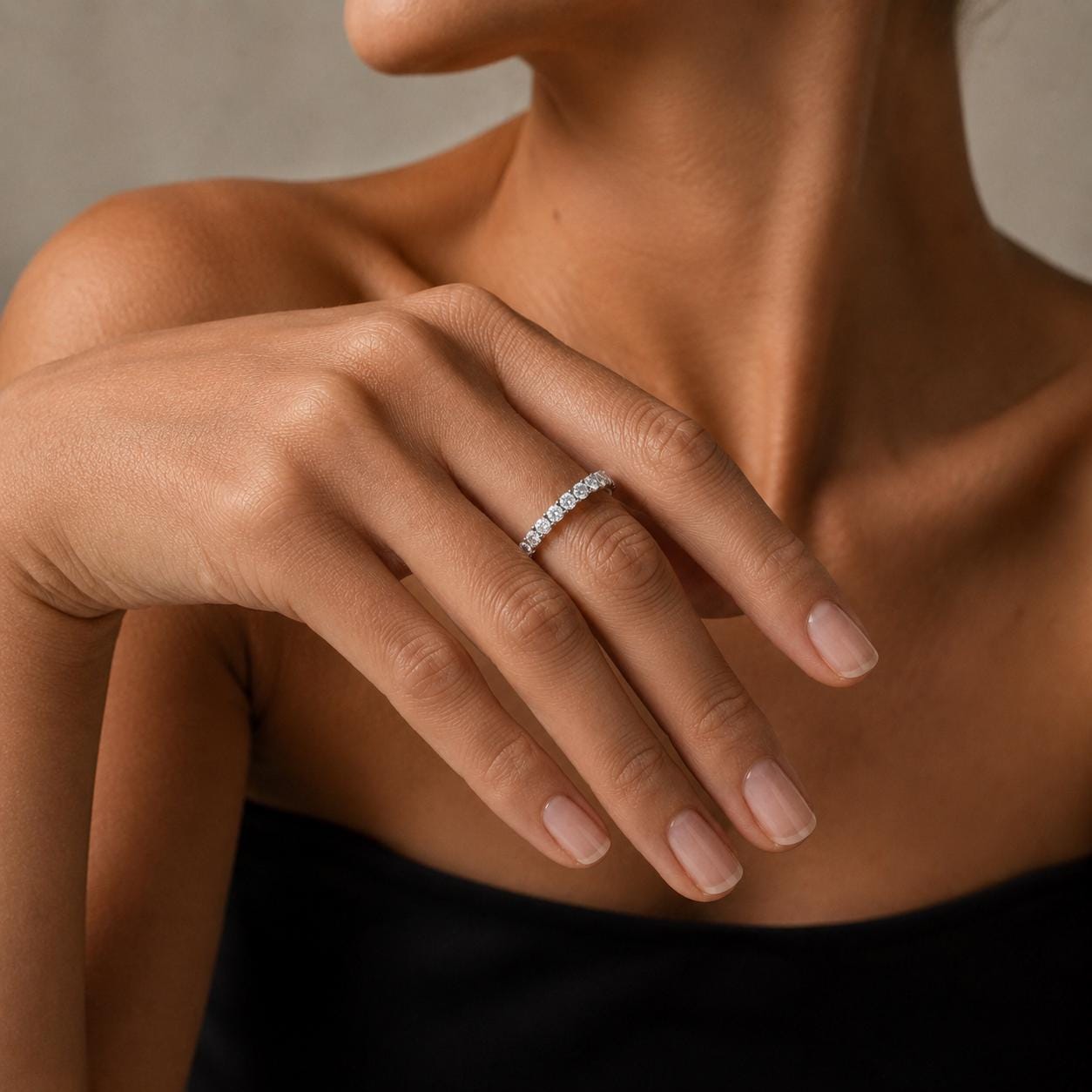 A close-up of a woman's hand wearing a diamond ring, with her fingers gently curled around the ring.