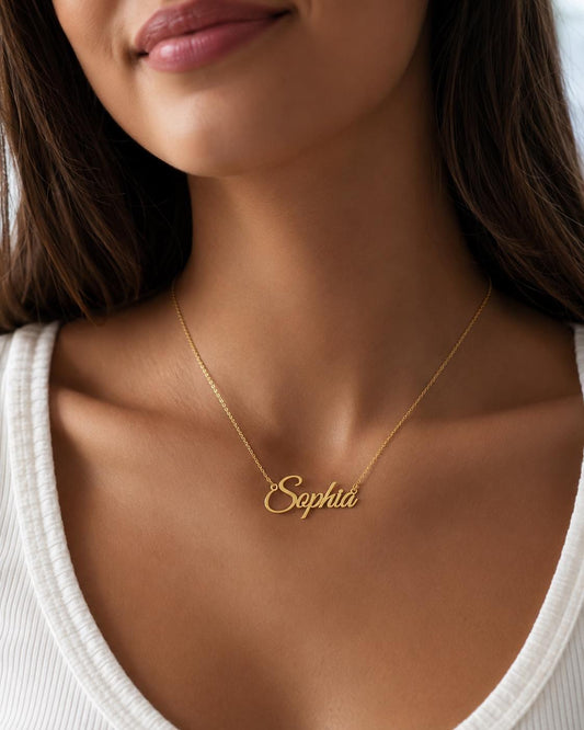 A close-up of a woman wearing a gold necklace with the name "Sophia" engraved on it.
