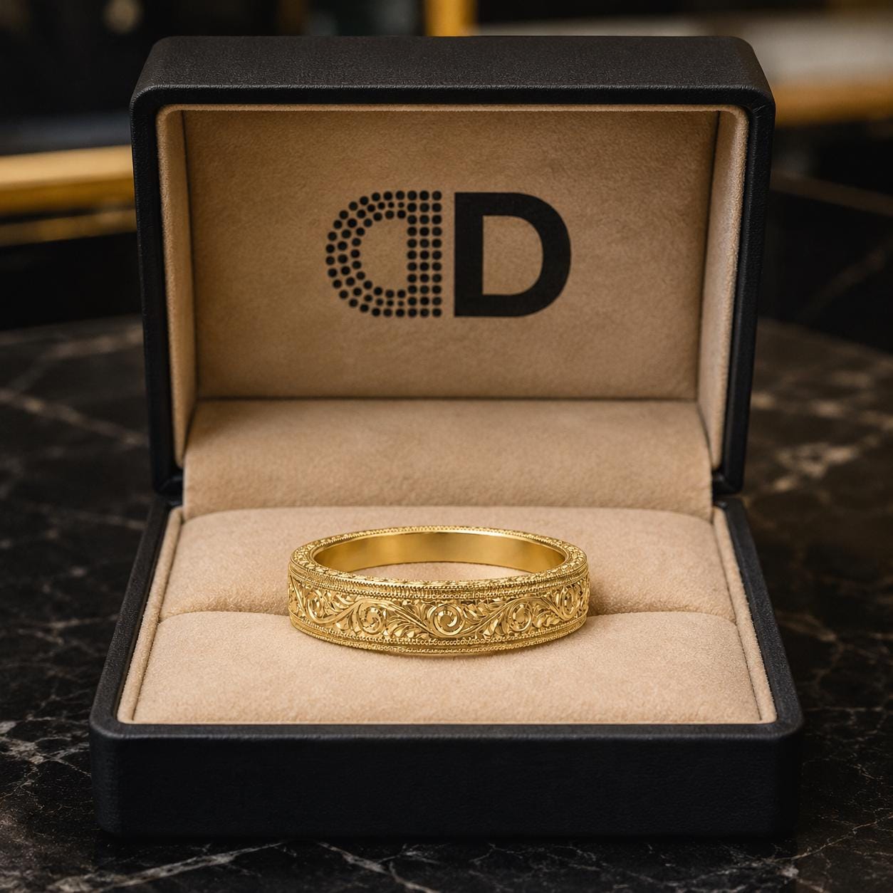 A gold ring is displayed in a black jewelry box with a logo on the inside.